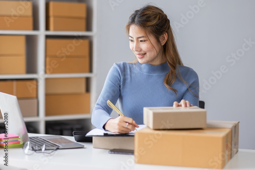 Portrait of asian young freelancer small business startup, SME owner, asian female entrepreneur work and check orders online at home. online SME business idea.