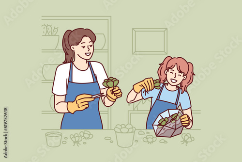 Mom and daughter make diy florarium by planting succulents in transparent aquarium to instill in child love of ecology. Happy girl makes florarium together with mother and dreams of becoming florist