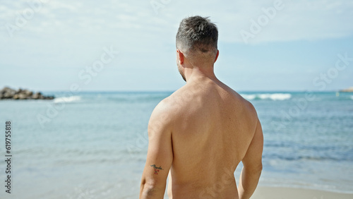 Young man tourist standing backwards looking around at the beach