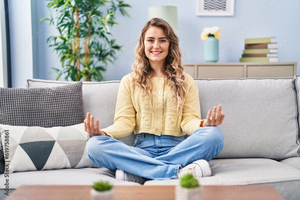 Young woman doing yoga exercise sitting on sofa at home Young woman doing yoga exercise sitting on sofa at home