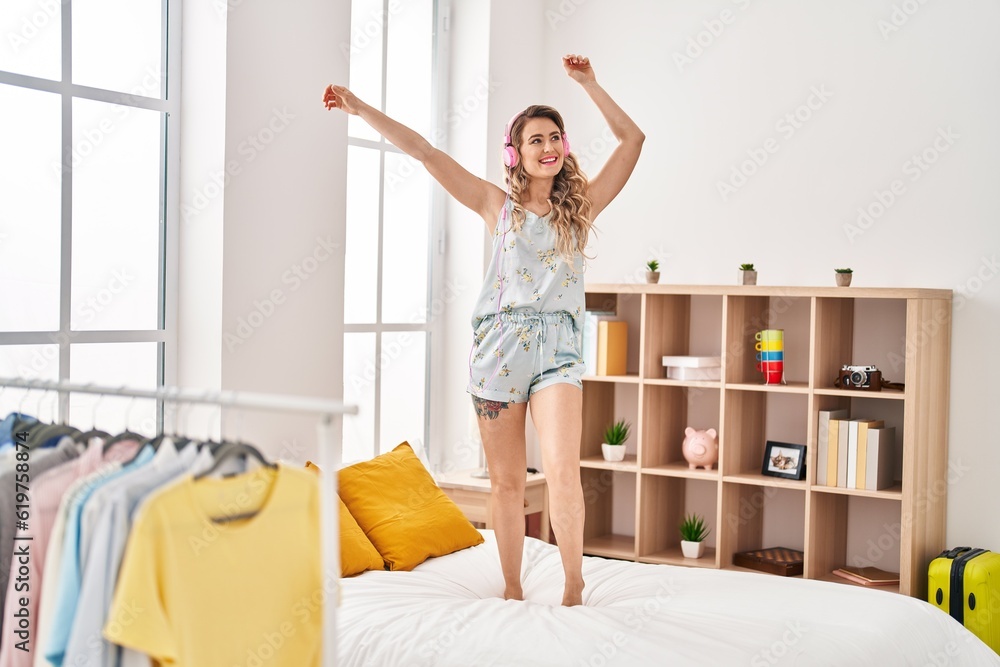 © Krakenimages.com - Young woman listening to music and dancing on bed at bedroom