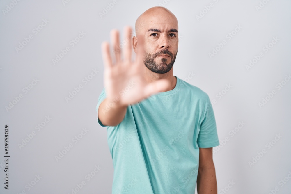 Middle age bald man standing over white background doing stop sing with palm of the hand. warning expression with negative and serious gesture on the face. Middle age bald man standing over white background doing stop sing with palm of the hand. warning expression with negative and serious gesture on the face.