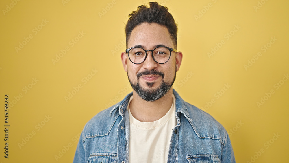 Fototapeta premium Young latin man smiling confident standing over isolated yellow background