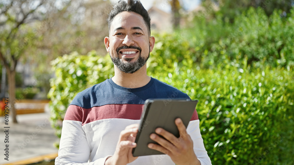 Young latin man smiling confident using touchpad at park Young latin man smiling confident using touchpad at park