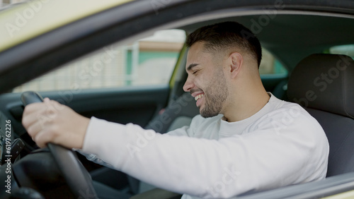 Young hispanic man smiling confident driving car at street