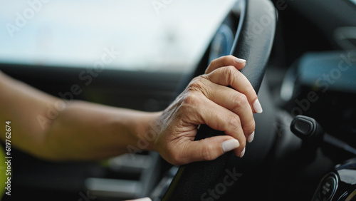 Middle age hispanic woman driving a car on the road