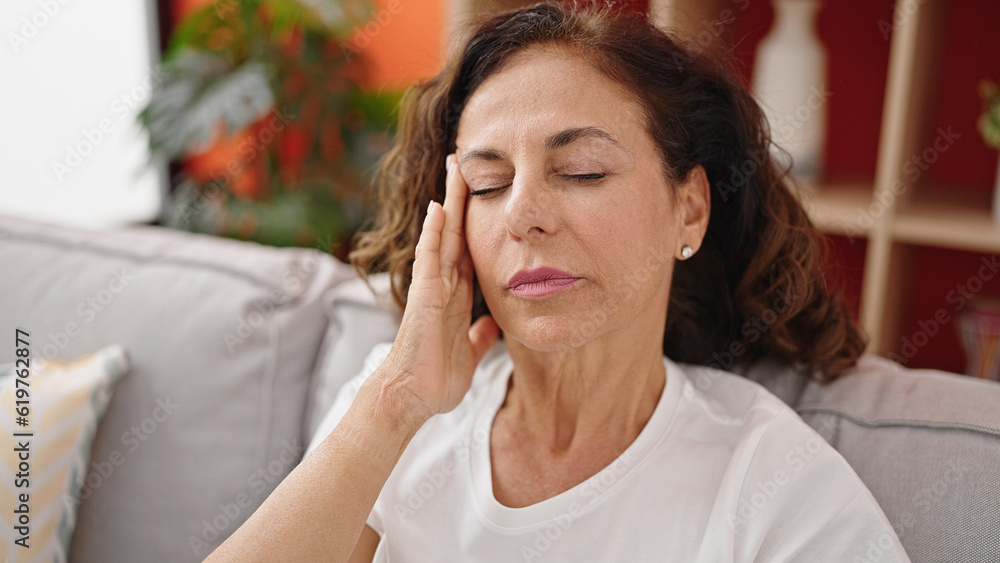 Middle age hispanic woman suffering for headache sitting on sofa at home Middle age hispanic woman suffering for headache sitting on sofa at home