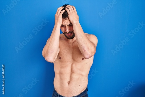 Fotografie Handsome hispanic man standing shirtless suffering from headache desperate and stressed because pain and migraine