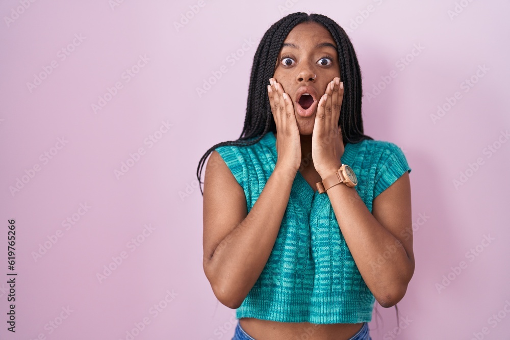 Young african american with braids standing over pink background afraid and shocked, surprise and amazed expression with hands on face Young african american with braids standing over pink background afraid and shocked, surprise and amazed expression with hands on face