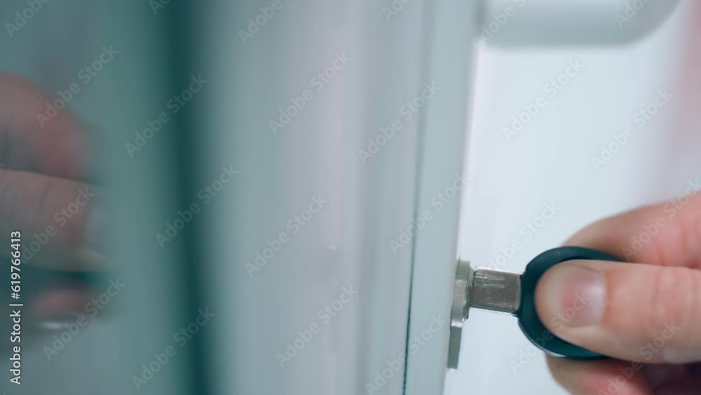 The key is poorly pulled out of the lock, close-up. A perforated key is inserted into the keyhole of white plastic doors. The key is poorly pulled out of the lock, close-up. A perforated key is inserted into the keyhole of white plastic doors.