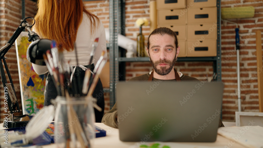 Man and woman couple using laptop and drawing at art studio