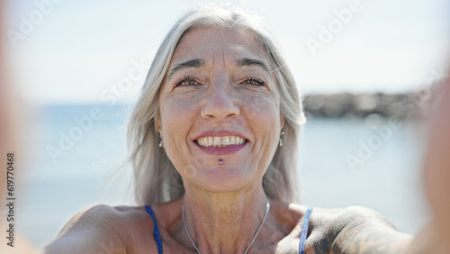 Middle age grey-haired woman tourist make selfie by camera at beach © Krakenimages.com