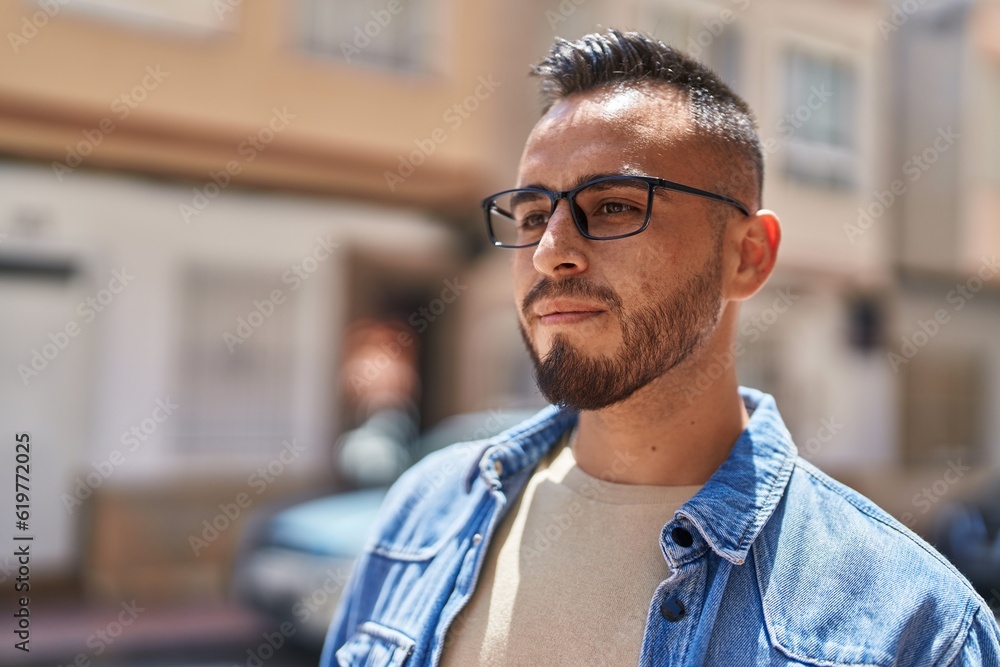 Young hispanic man with relaxed expression wearing glasses at street Young hispanic man with relaxed expression wearing glasses at street