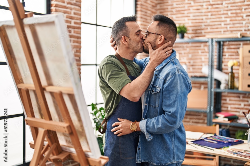 Two men artists hugging each other kissing at art studio Two men artists hugging each other kissing at art studio