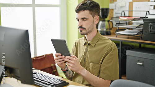 Young hispanic man business worker using computer and touchpad working at office