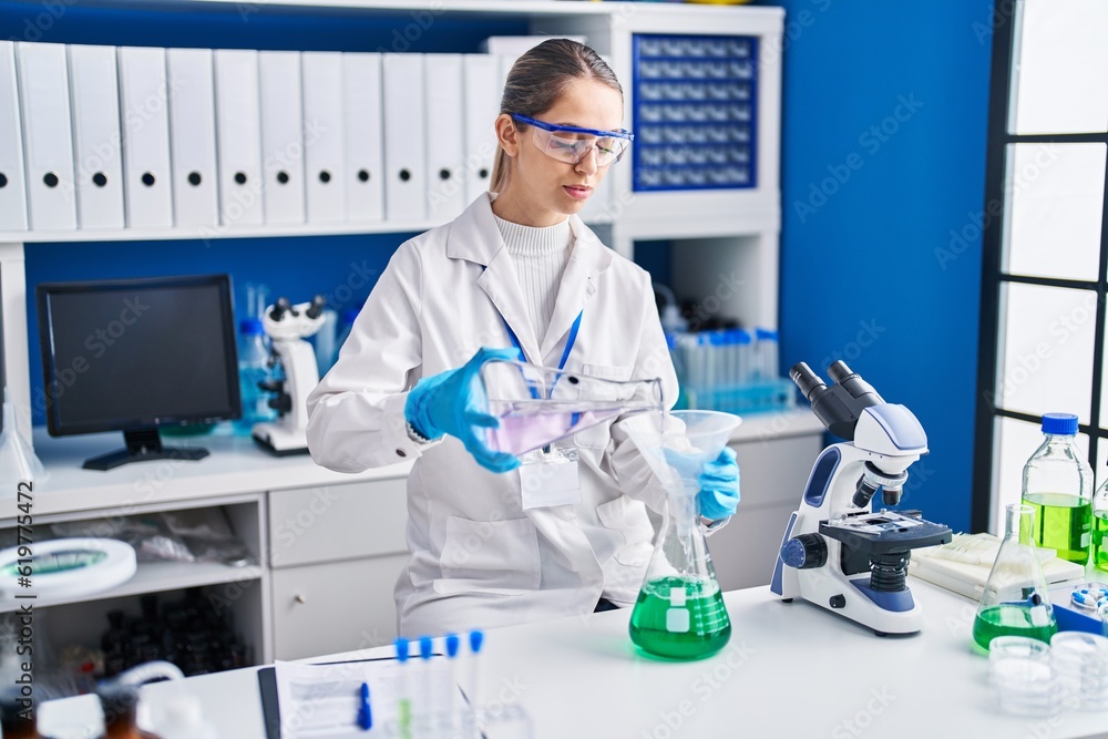 Young woman scientist measuring liquid at laboratory Young woman scientist measuring liquid at laboratory
