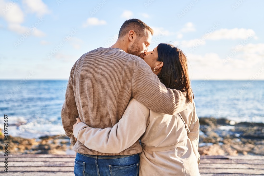 Man and woman couple hugging each other kissing at seaside