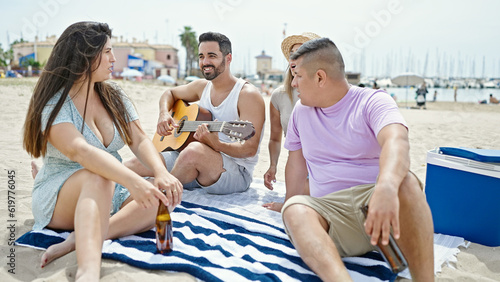 Group of people playing guitar drinking beer singing song at beach