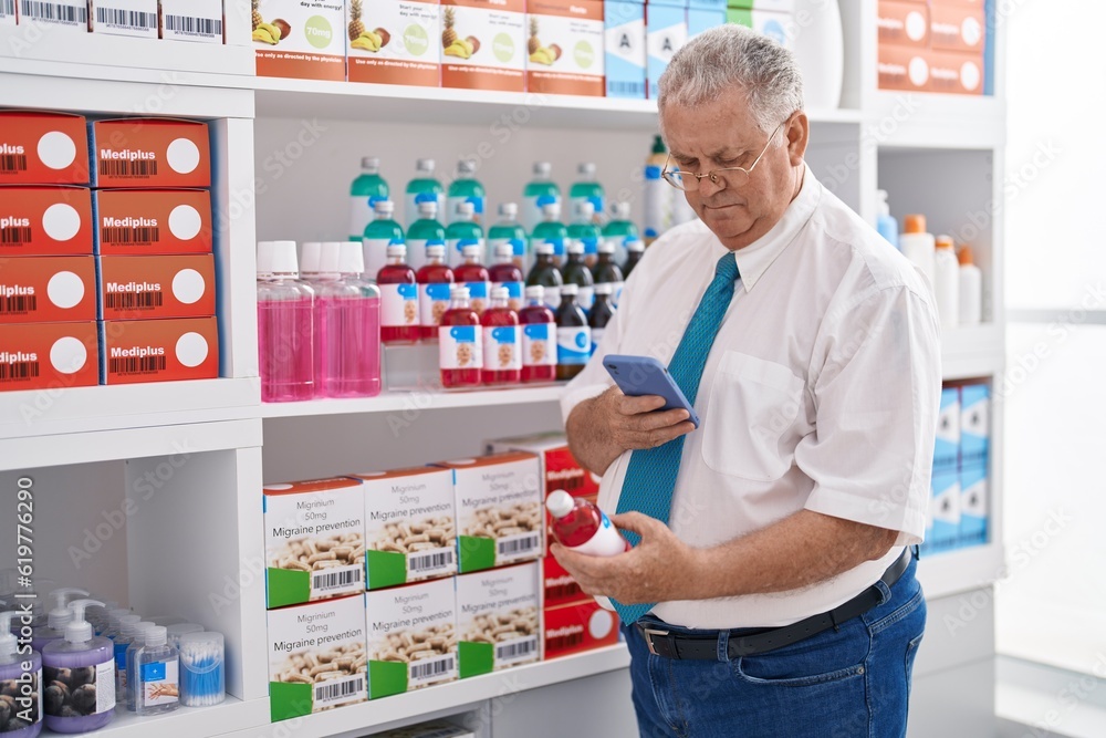 Middle age grey-haired man customer make photo by smartphone to medicine bottle at pharmacy
