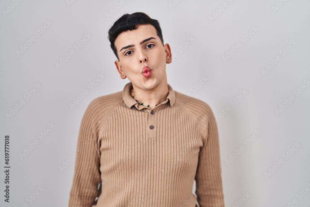 Non binary person standing over isolated background making fish face with lips, crazy and comical gesture. funny expression. Non binary person standing over isolated background making fish face with lips, crazy and comical gesture. funny expression.