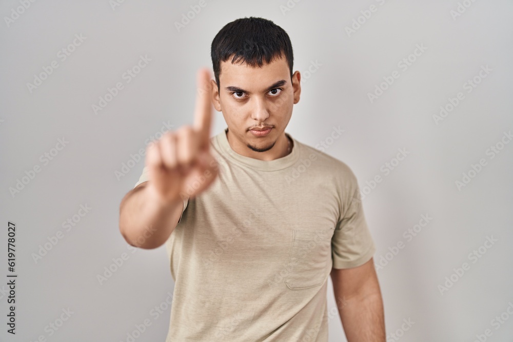 Young arab man wearing casual t shirt pointing with finger up and angry expression, showing no gesture Young arab man wearing casual t shirt pointing with finger up and angry expression, showing no gesture