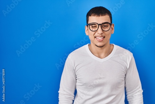 Wallpaper Mural Young arab man wearing casual white shirt and glasses winking looking at the camera with sexy expression, cheerful and happy face. Torontodigital.ca