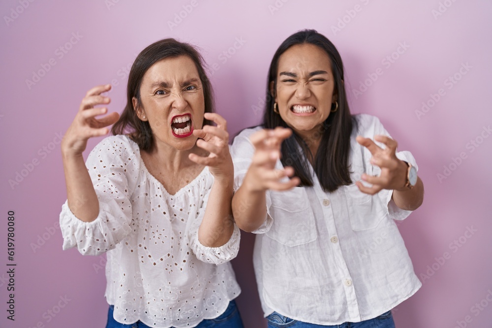 Hispanic mother and daughter together shouting frustrated with rage, hands trying to strangle, yelling mad Hispanic mother and daughter together shouting frustrated with rage, hands trying to strangle, yelling mad