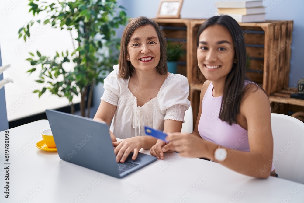 Two women mother and daughter using laptop and credit card at home Two women mother and daughter using laptop and credit card at home