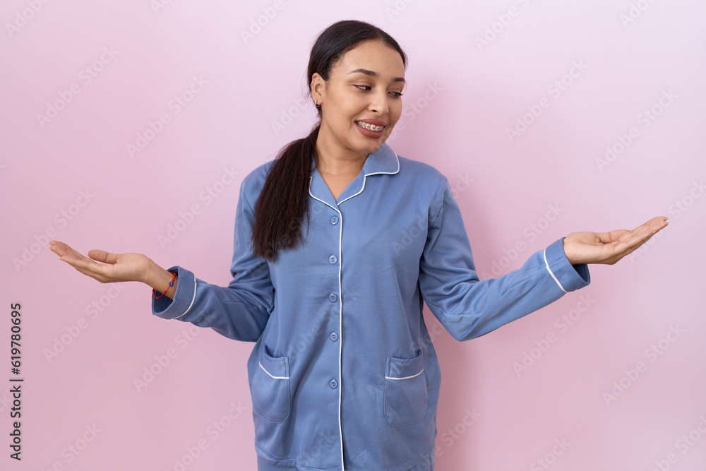 Young arab woman wearing blue pajama smiling showing both hands open palms, presenting and advertising comparison and balance Young arab woman wearing blue pajama smiling showing both hands open palms, presenting and advertising comparison and balance