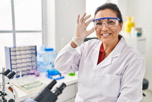 Middle age hispanic woman wearing scientist uniform working at laboratory