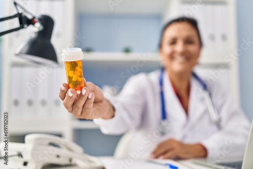 Middle age hispanic woman wearing doctor uniform prescribe pills at clinic