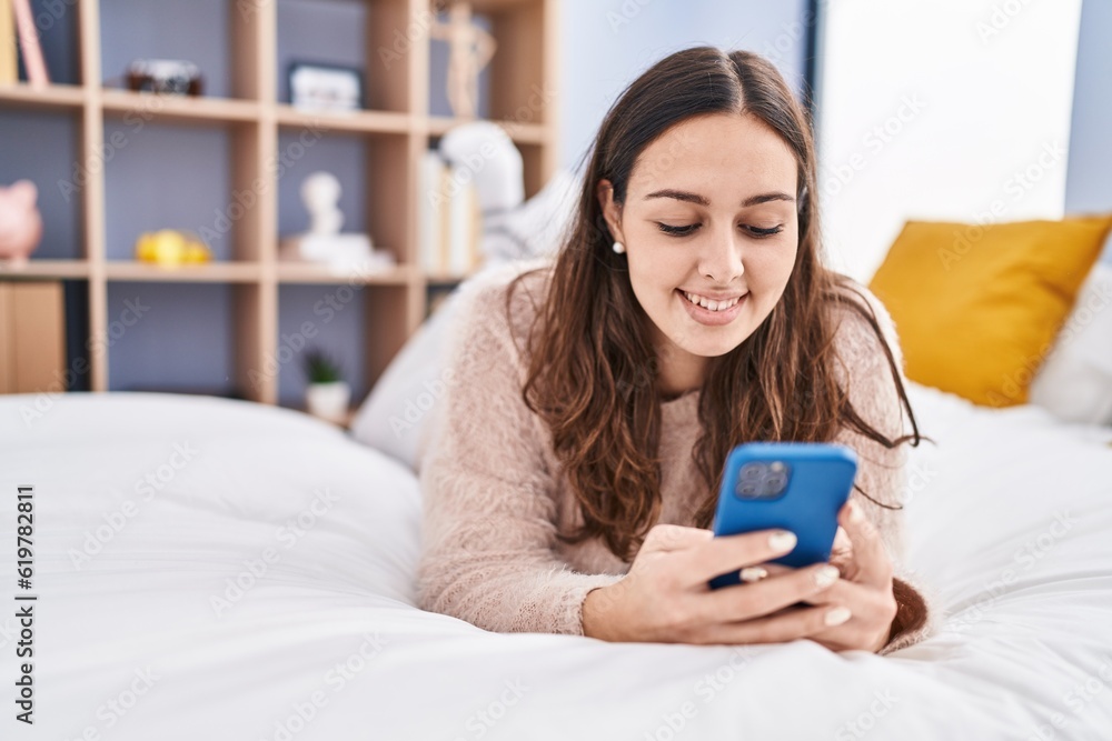 Young beautiful hispanic woman using smartphone lying on bed at bedroom Young beautiful hispanic woman using smartphone lying on bed at bedroom