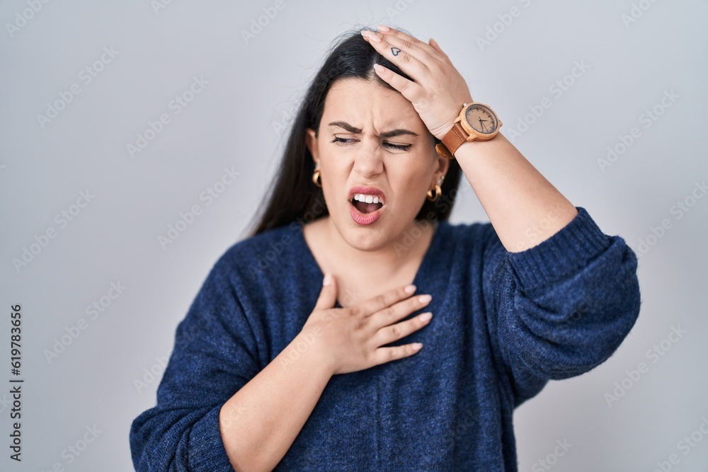 Young brunette woman standing over isolated background touching forehead for illness and fever, flu and cold, virus sick Young brunette woman standing over isolated background touching forehead for illness and fever, flu and cold, virus sick