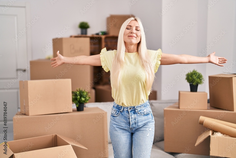 Young blonde woman standing with open arms at new home Young blonde woman standing with open arms at new home