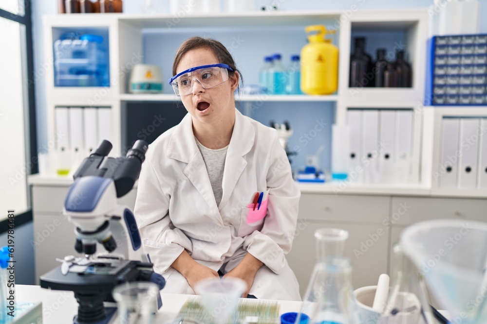 Hispanic girl with down syndrome working at scientist laboratory looking sleepy and tired, exhausted for fatigue and hangover, lazy eyes in the morning. Hispanic girl with down syndrome working at scientist laboratory looking sleepy and tired, exhausted for fatigue and hangover, lazy eyes in the morning.