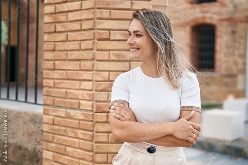 Young caucasian woman smiling confident standing with arms crossed gesture at street