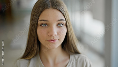 Young beautiful girl sitting on table with serious face at library