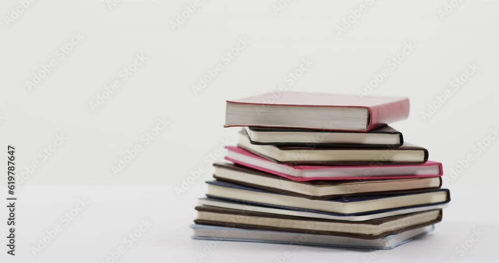 Close up of stack of books on white background, in slow motion