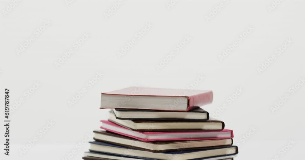 Close up of stack of books on white background, in slow motion Close up of stack of books on white background, in slow motion