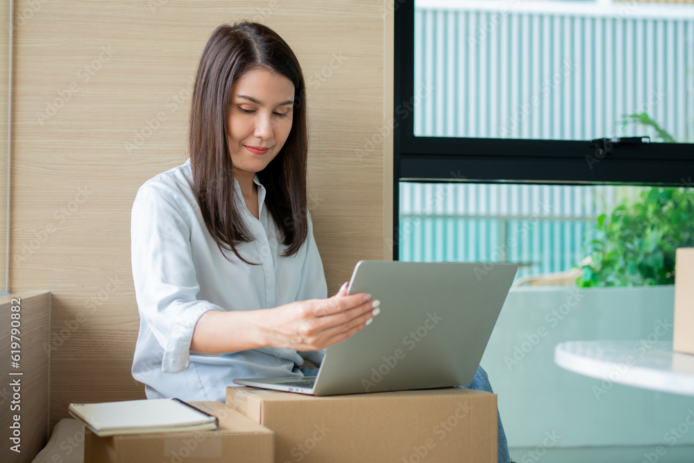 Happy young Asian woman entrepreneur, Smile for sales success after checking order from online shopping store in a laptop at home office, Concept of merchant business online and eCommerce Happy young Asian woman entrepreneur, Smile for sales success after checking order from online shopping store in a laptop at home office, Concept of merchant business online and eCommerce