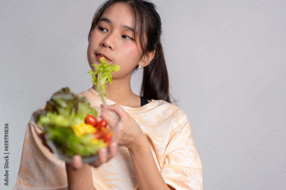 Portrait of a happy playful Asian girl eating fresh salad from a glass bowl after workout at home. Young lady Enjoying Healthy Nutrition And Organic Food, Having Vegetarian Meal Portrait of a happy playful Asian girl eating fresh salad from a glass bowl after workout at home. Young lady Enjoying Healthy Nutrition And Organic Food, Having Vegetarian Meal
