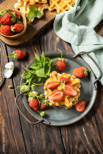 Belgian waffles with fresh berrie strawberries and ricotta cheese for breakfast on a rustic table. Copy space.