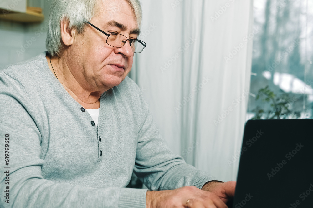 Old man Thinking at Laptop. Pensive Mature Grey hair 60s - 70s Aged Man Sitting at Table with laptop. Thoughtful retired Senior male works online at computer from home, Solving Problems with Solutions Old man Thinking at Laptop. Pensive Mature Grey hair 60s - 70s Aged Man Sitting at Table with laptop. Thoughtful retired Senior male works online at computer from home, Solving Problems with Solutions