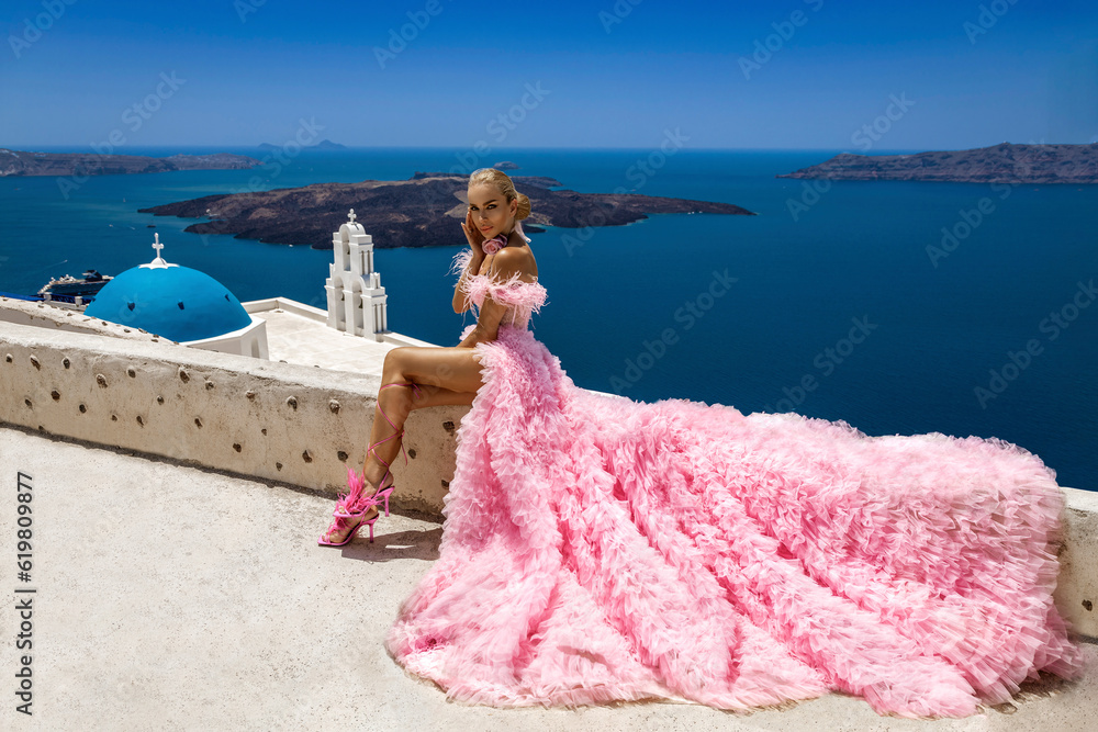 Glamour, stylish elegant bride woman in pink long wedding dress is posing near Church of the Three Bells in Fira in Santorini. - obrazy, fototapety, plakaty 