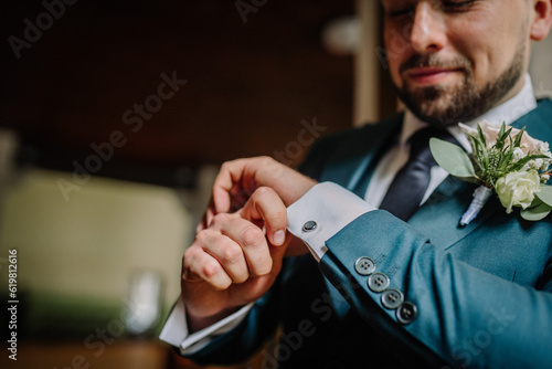 Man wearing suite, adjusting cufflink, mid section, close-up photo