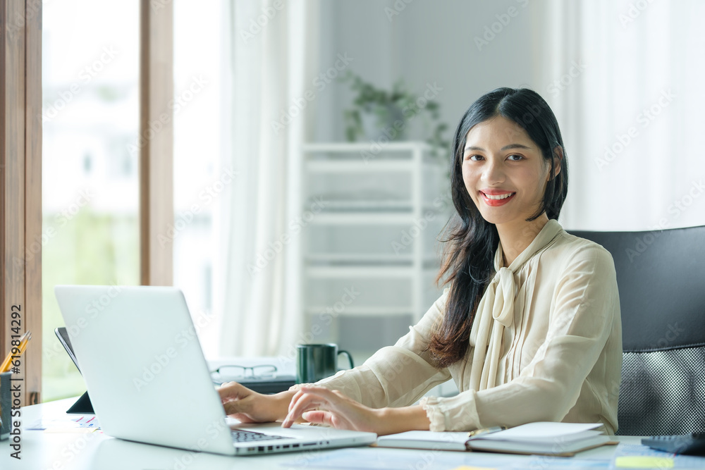 Asian businesswoman sitting at her office desk and smiling to camera. Asian businesswoman sitting at her office desk and smiling to camera.