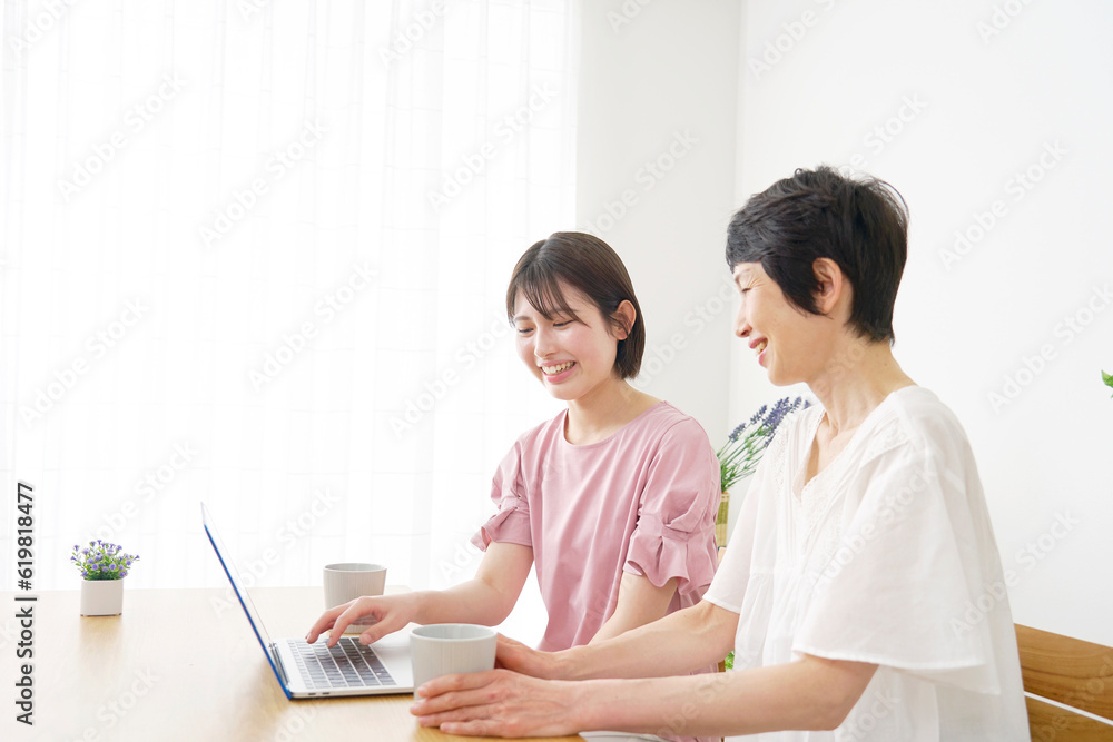 自宅でノートパソコンを使う母親と娘