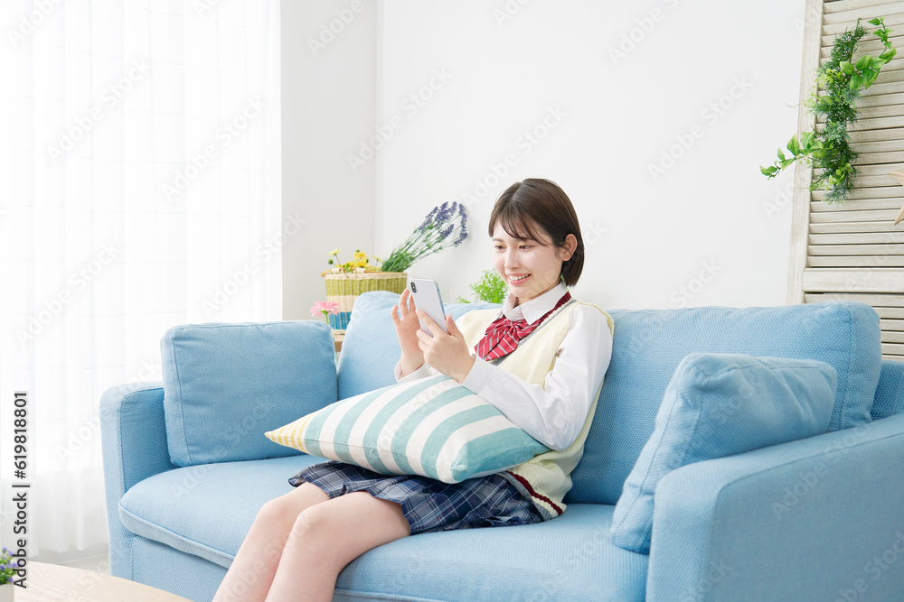 自宅でスマートフォンを使う女子高生 自宅でスマートフォンを使う女子高生