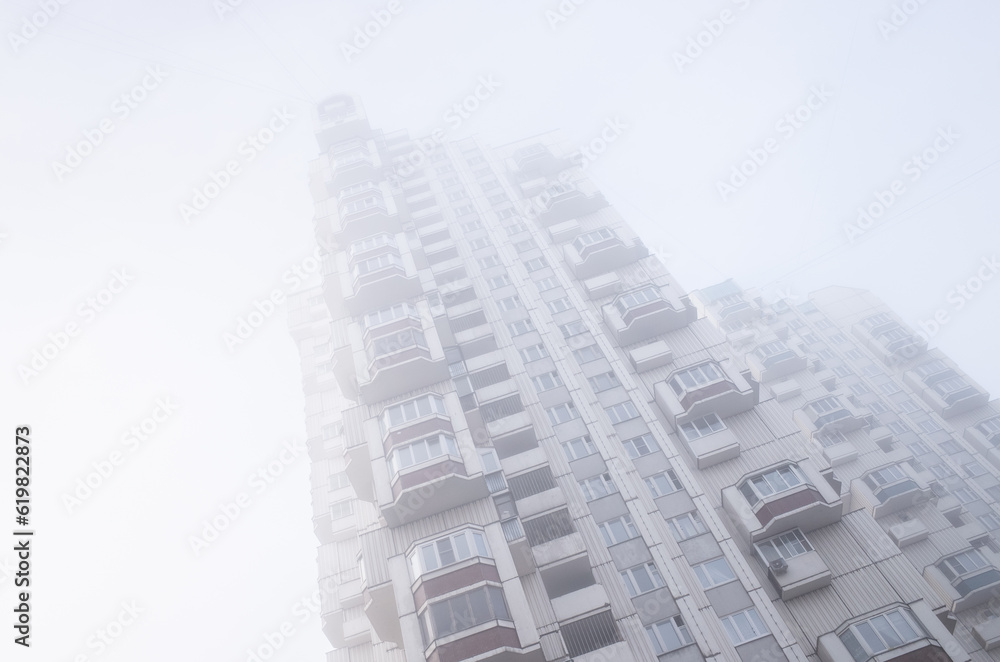 Tall residential buildings in the form of a tower, immersed in a misty sky. Cyberpunk stylistics. Dramatic, depressing mood Tall residential buildings in the form of a tower, immersed in a misty sky. Cyberpunk stylistics. Dramatic, depressing mood