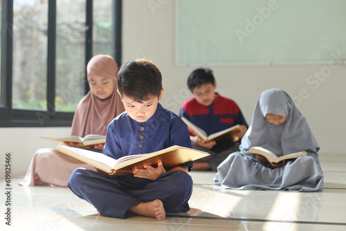 Canvas Print Selective focus of Muslim children reading Koran or Quran together